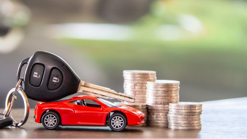 is getting a car loan a good idea? Image of toy car + keys and money on a table