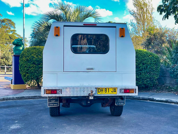 Tradie 4x4 for sale - Mitsubishi Triton with 3 way storage unit at the back - photo showing the rear of the vehicle with lockable steel canopy doors and protected lights and towbar