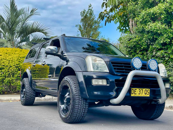 Dual Cab UTE for Sale - Great Online Reviews - Model Shown is the 5 person dual cab Holden Colorado in Black 2006 - photo showing the front drivers side angle of the vehicle from a low down angle showing the fat tyres, roo bars and spot lights