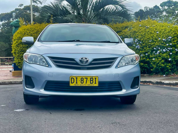 Used Toyota Corolla for sale - Model shown is a light blue 2005 Automatic in great condition - Photo showing the front straight on view with colour coded bumper and front grille