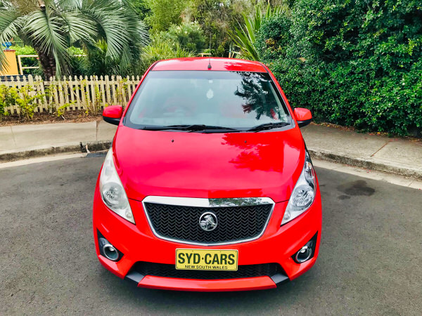 Used Holden Barina for sale in Sydney - Model shown is the 2011 Holden Barina Spark CDX in Red - photo shows a close up of the front grille and the matching paintwork on the front bumper