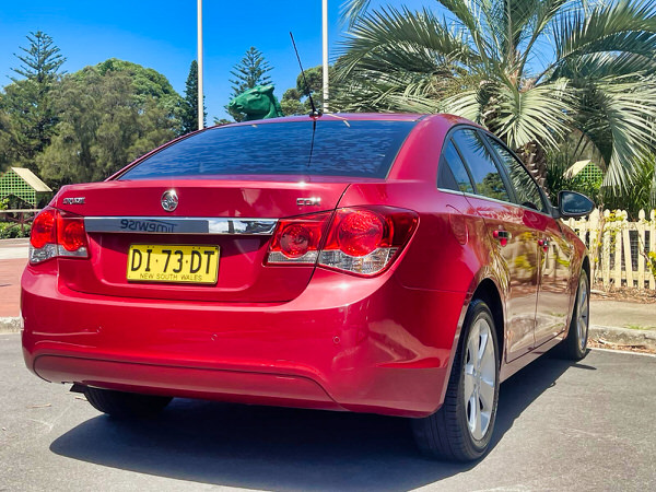 Used Holden Cruze for sale in Sydney - Automatic 2010 Maroon model - Photo showing the rear drivers side picture taken from a low angle