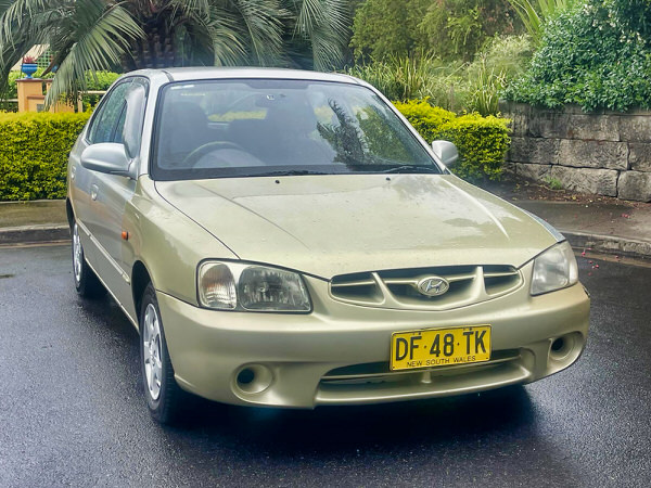 Used Hyundai Accent for sale in Sydney - Gold Automatic 2001 GLS 5 door hatchback model in great condition - photo showing the front passenger side angle view shot from a low angle